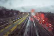 Raindrops fall while the Airtrain streaks by bumper to bumper traffic on the Van Wyck Expressway